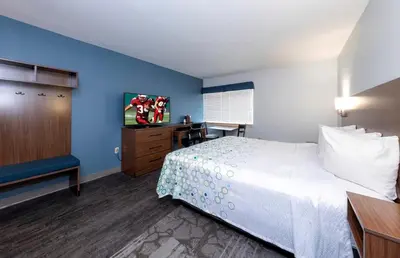 a hotel room with a bed and a flat screen tv at HomeTowne Studios by Red Roof Wilmington - New Castle in New Castle