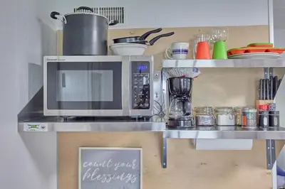 a kitchen counter with a microwave on a shelf at Fairway Paradise tiny home in Lancaster