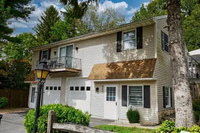 a white house with a porch and a tree at Fairway Paradise tiny home in Lancaster