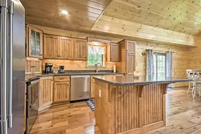 a kitchen with wooden cabinets and a large counter top at Lake View and Hot Tub Wrightsville Cabin! in Wrightsville