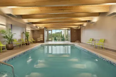 a pool in a hotel with green chairs and a ceiling at Home2 Suites By Hilton Ephrata in Ephrata