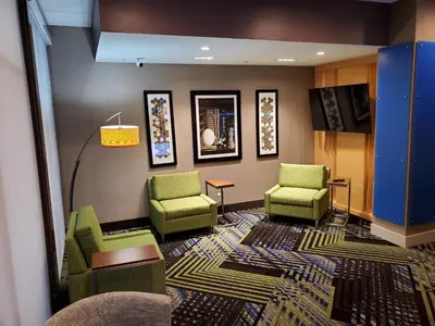 a waiting room with green chairs and a tv at Holiday Inn Express & Suites - Harrisburg S - Mechanicsburg by IHG in Mechanicsburg