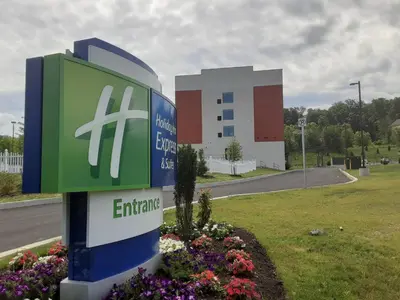 a sign for an entrance to a building with flowers at Holiday Inn Express & Suites - Harrisburg S - Mechanicsburg by IHG in Mechanicsburg