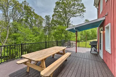 a wooden picnic table on the deck of a red building at The Millersburg Mountain House Getaway with Gazebo! in Millersburg
