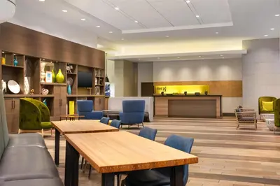 a lobby with wooden tables and blue chairs at Home2 Suites by Hilton Philadelphia Convention Center in Philadelphia