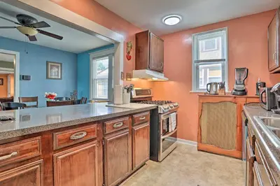 a large kitchen with orange walls and wooden cabinets at Suburban Home with Backyard Patio Less Than 7 Miles to Dtwn! in Lansdowne