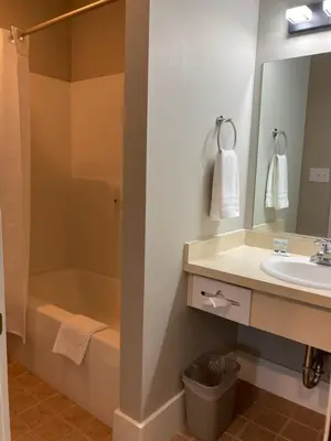 a bathroom with a sink and a shower and a mirror at Country Squire Inn and Suites in New Holland
