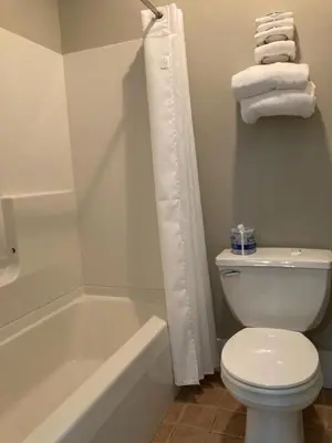a bathroom with a white toilet and a tub and a sink at Country Squire Inn and Suites in New Holland