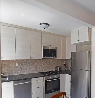 a kitchen with white cabinets and a stainless steel refrigerator at Riverhouse Extended Stay Apartment in Jersey City