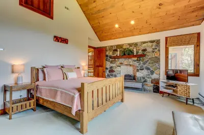 a bedroom with a bed and a stone fireplace at Peaceful Mountian Oasis Firepit, Hot Tub, Sauna! in Vernon Township