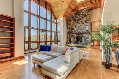 a living room with a white couch and a stone fireplace at Peaceful Mountian Oasis Firepit, Hot Tub, Sauna! in Vernon Township