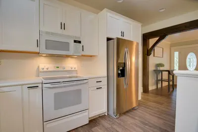 a kitchen with white cabinets and a stainless steel refrigerator at Waterfront Home with Hot Tub in Wrightsville! in Wrightsville