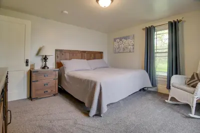 a bedroom with a bed and a chair and a window at Waterfront Home with Hot Tub in Wrightsville! in Wrightsville