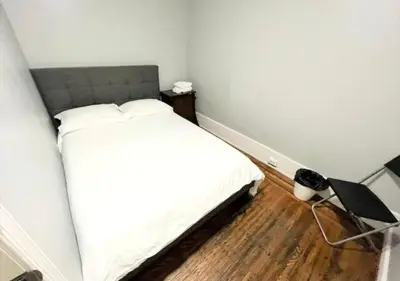 a bedroom with a white bed and a wooden floor at Clover 2900 - Apartment and Rooms with Private Bathroom near Washington Ave South Philly in Philadelphia