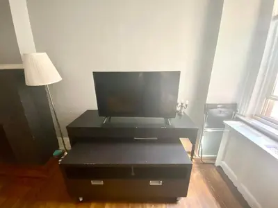 a tv sitting on top of a black entertainment center at Clover 2900 - Apartment and Rooms with Private Bathroom near Washington Ave South Philly in Philadelphia