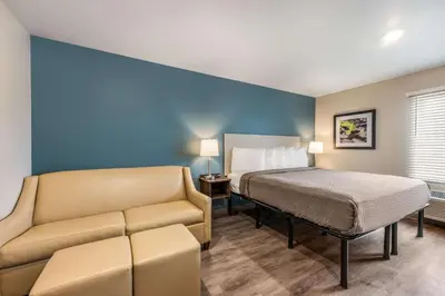 a hotel room with a bed and a couch at WoodSpring Suites Linden in Linden