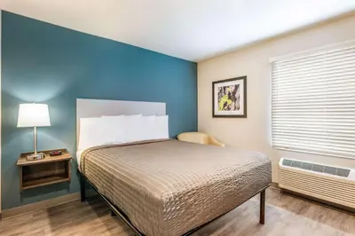 a bedroom with a bed and a blue wall at WoodSpring Suites Linden in Linden