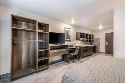 a hotel room with a bed and a desk with a television at WoodSpring Suites Linden in Linden
