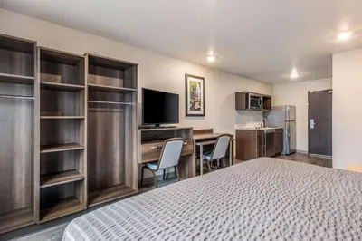 a hotel room with a bed and a desk and a kitchen at WoodSpring Suites Linden in Linden