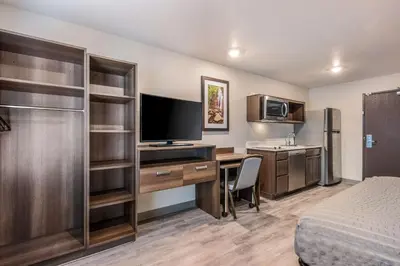 a hotel room with a bed and a desk with a television at WoodSpring Suites Linden in Linden