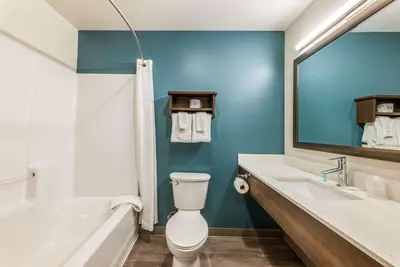 a bathroom with a toilet and a tub and a sink at WoodSpring Suites Linden in Linden
