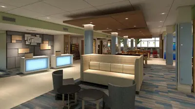 a lobby with two monitors and tables and chairs at Holiday Inn Express & Suites - Lancaster - Mount Joy by IHG in Mount Joy