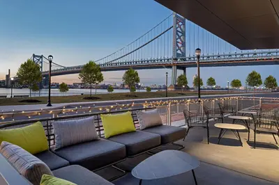 a view of a bridge with a couch and tables and chairs at Hilton Garden Inn Camden Waterfront Philadelphia in Camden