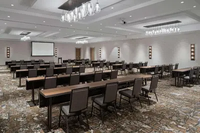 a conference room with tables and chairs and a screen at Hilton Garden Inn Camden Waterfront Philadelphia in Camden