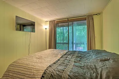a bedroom with a bed in front of a window at Quaint Lake Cottage with Pool and Beach Access! in Pocono Lake