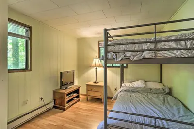 a bedroom with a bunk bed and a television at Quaint Lake Cottage with Pool and Beach Access! in Pocono Lake
