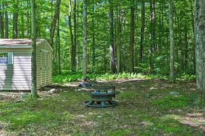 a picnic table in the woods next to a cabin at Quaint Lake Cottage with Pool and Beach Access! in Pocono Lake