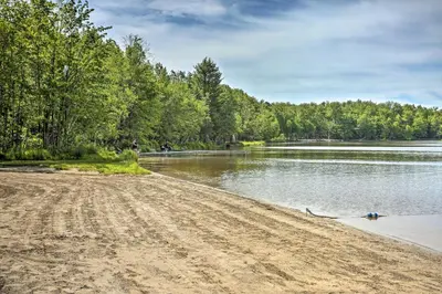 a sandy beach next to a body of water at Quaint Lake Cottage with Pool and Beach Access! in Pocono Lake