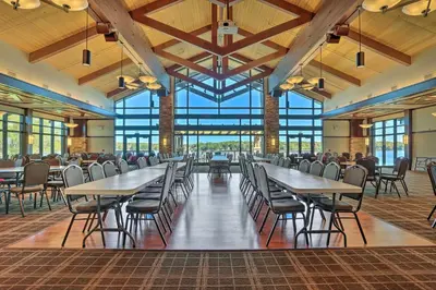 a dining hall with tables and chairs and windows at Quaint Lake Cottage with Pool and Beach Access! in Pocono Lake