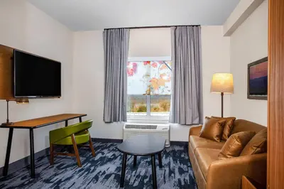a living room with a couch and a table and a window at Fairfield by Marriott Inn & Suites Harrisburg West/Mechanicsburg in Mechanicsburg