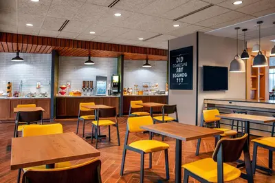 a restaurant with wooden tables and yellow chairs at Fairfield by Marriott Inn & Suites Harrisburg West/Mechanicsburg in Mechanicsburg