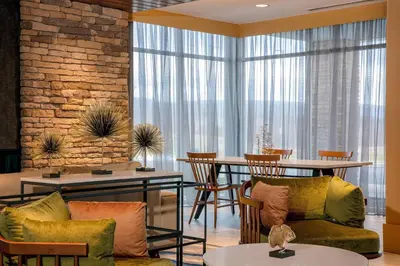 a living room with chairs and tables and a brick wall at Fairfield by Marriott Inn & Suites Harrisburg West/Mechanicsburg in Mechanicsburg