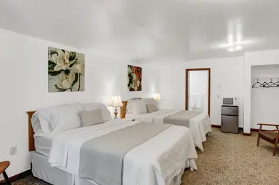 two beds in a hotel room with white walls at Halifax Inn in Halifax