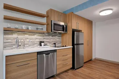 a kitchen with stainless steel appliances and wooden cabinets at Element New York Wood Ridge in Wood-Ridge