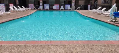 a large blue swimming pool with chairs in a hotel at HomeTowne Studios by Red Roof Bordentown - McGuire AFB in Bordentown