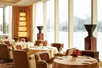 a restaurant with tables and chairs and a large window at Casa Cipriani New York in New York