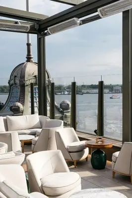 a room with white chairs and a view of the water at Casa Cipriani New York in New York