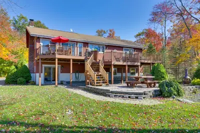 a large house with a deck and a picnic table at Ski, Swim and Relax Waterfront Haven on Pines Lake! in Pocono Lake