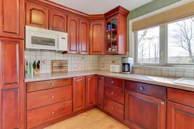 a kitchen with wooden cabinets and a microwave at Ski, Swim and Relax Waterfront Haven on Pines Lake! in Pocono Lake