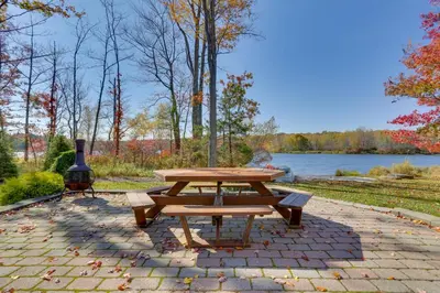 a picnic table sitting on a brick patio next to a lake at Ski, Swim and Relax Waterfront Haven on Pines Lake! in Pocono Lake