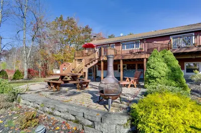 a house with a deck and a grill and a picnic table at Ski, Swim and Relax Waterfront Haven on Pines Lake! in Pocono Lake