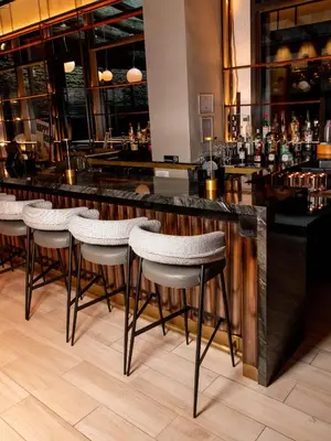 a bar with white stools in a restaurant at The Draper New York, Tapestry Collection by Hilton in New York