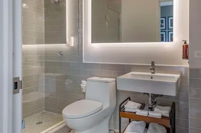 a bathroom with a toilet and a sink and a mirror at The Draper New York, Tapestry Collection by Hilton in New York
