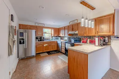 a kitchen with wooden cabinets and a stainless steel refrigerator at Luxurious house with largest hot tub & perfect retreat! in Lake Harmony