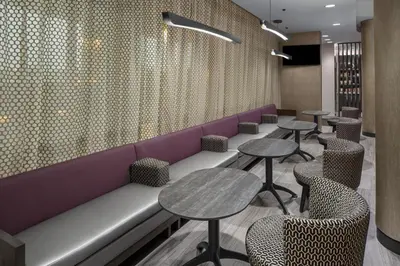 a restaurant with tables and chairs and a purple couch at SpringHill Suites by Marriott East Rutherford Meadowlands Carlstadt in Carlstadt