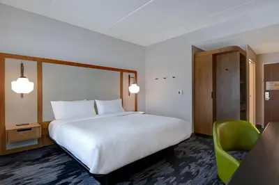 a bedroom with a large bed and a green chair at Fairfield Inn & Suites by Marriott Selinsgrove in Selinsgrove